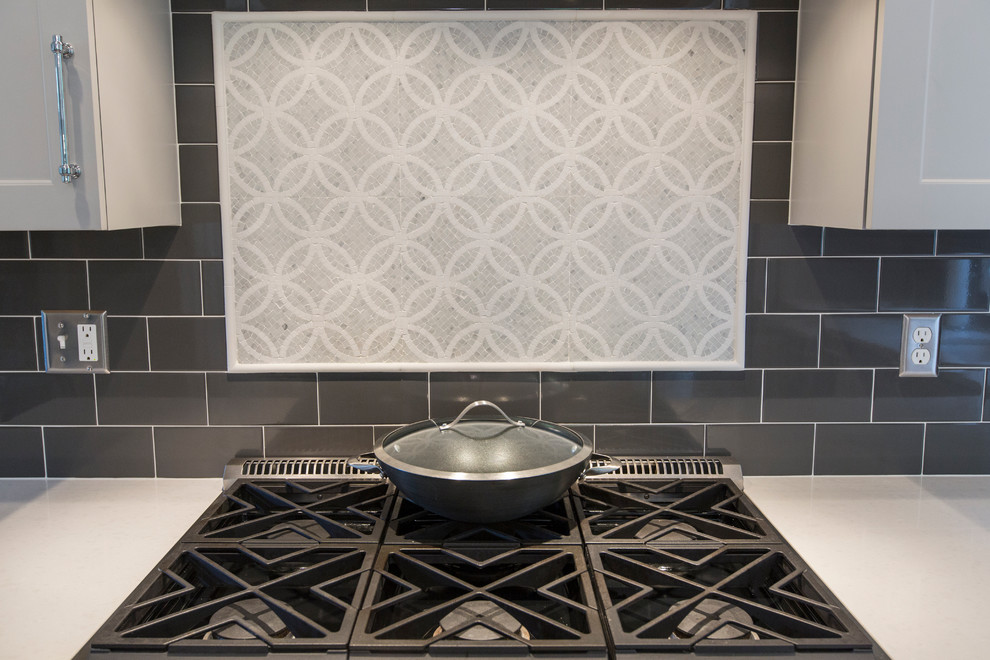 Inspiration for a mid-sized transitional l-shaped medium tone wood floor eat-in kitchen remodel in Bridgeport with an undermount sink, recessed-panel cabinets, gray cabinets, granite countertops, black backsplash, ceramic backsplash, stainless steel appliances and an island