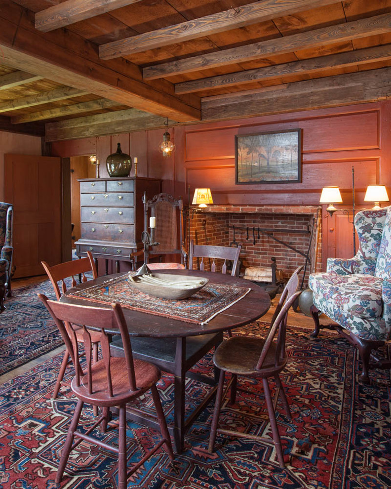 This is an example of a country dining room in Boston with red walls and a standard fireplace.