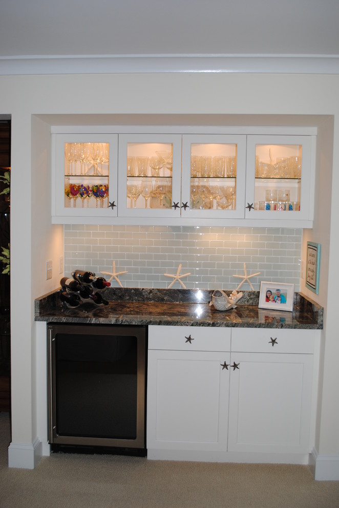 Design ideas for a small beach style single-wall wet bar in Other with glass-front cabinets, white cabinets, granite benchtops, blue splashback, ceramic splashback and carpet.