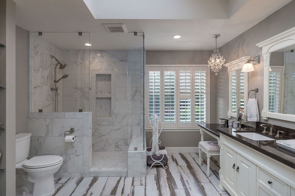 Inspiration for a mid-sized traditional master bathroom in San Francisco with furniture-like cabinets, white cabinets, a corner shower, a two-piece toilet, marble, grey walls, porcelain floors, an undermount sink, engineered quartz benchtops, multi-coloured floor, a hinged shower door and black benchtops.