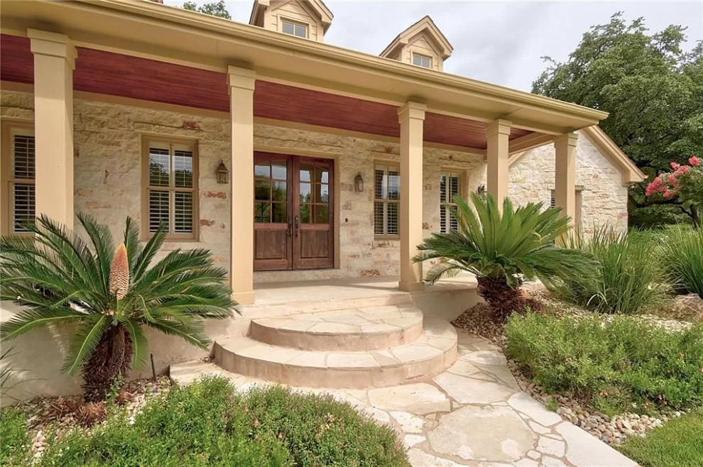 Large arts and crafts front yard verandah in Austin with with columns, natural stone pavers and a roof extension.