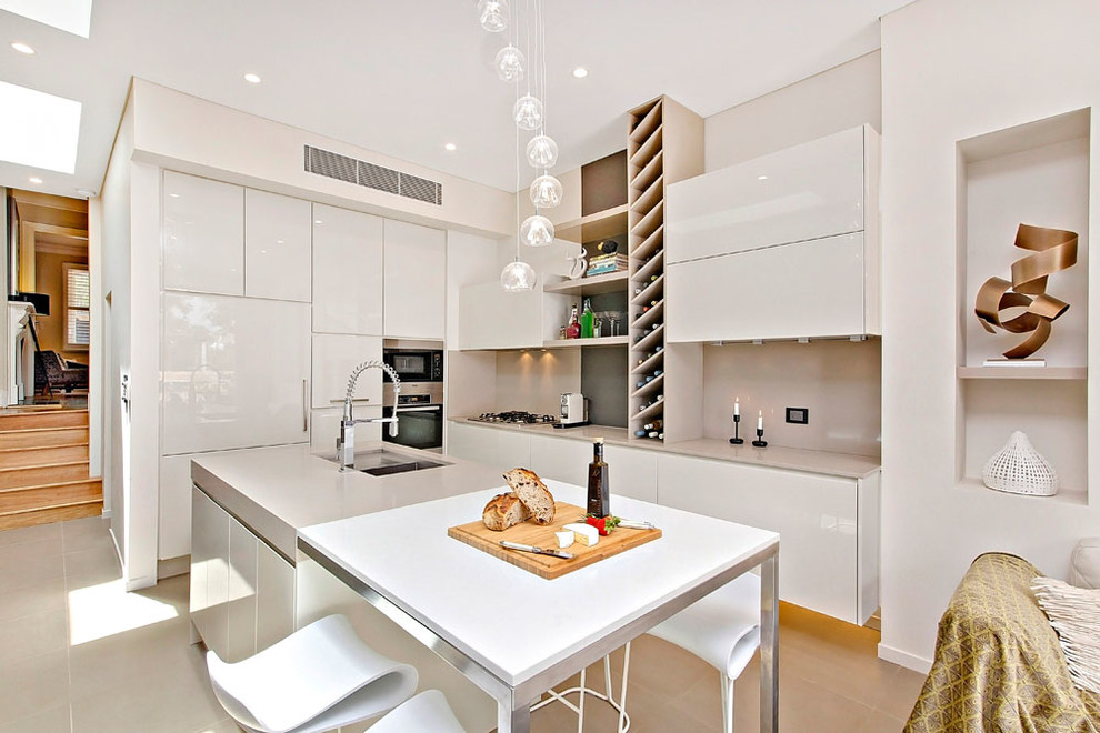 Inspiration for a contemporary l-shaped open plan kitchen in Sydney with an undermount sink, flat-panel cabinets, white cabinets, beige splashback, stone slab splashback, panelled appliances and with island.
