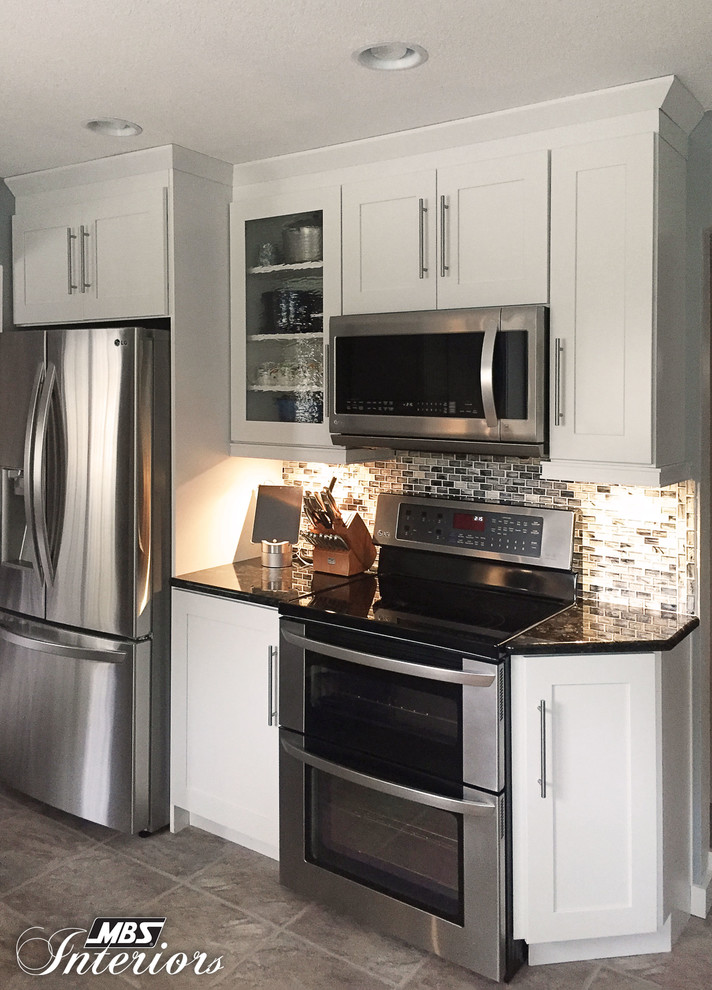 Inspiration for a mid-sized transitional galley ceramic tile and beige floor eat-in kitchen remodel with a farmhouse sink, white cabinets, stainless steel appliances, shaker cabinets, granite countertops, blue backsplash, glass sheet backsplash and an island