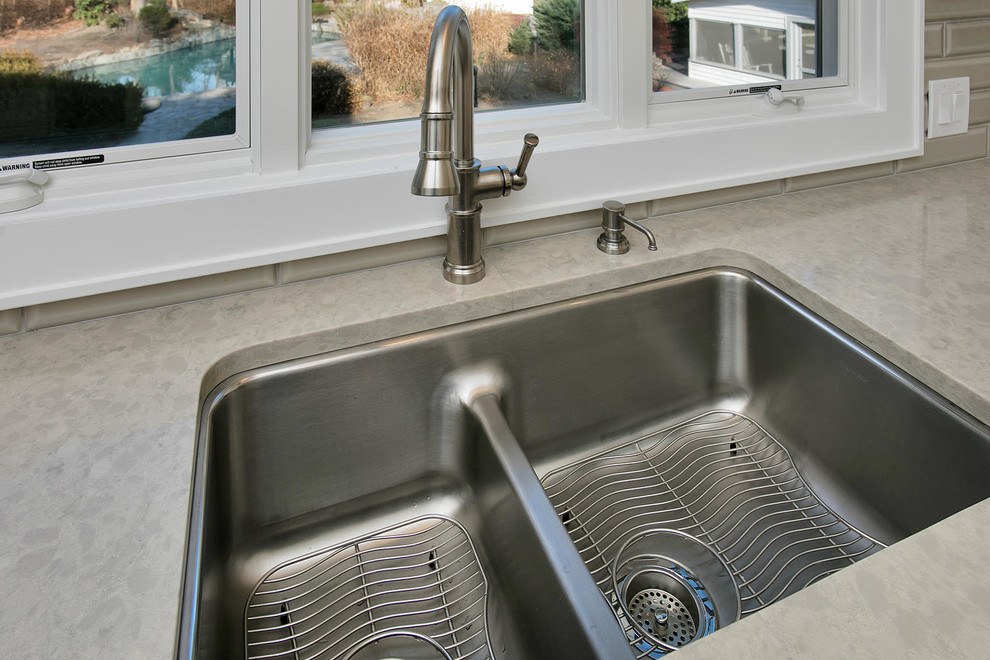 Example of a mid-sized transitional u-shaped porcelain tile eat-in kitchen design in New York with an undermount sink, recessed-panel cabinets, white cabinets, wood countertops, gray backsplash, subway tile backsplash, stainless steel appliances and an island