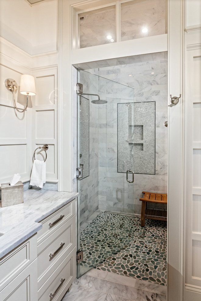 This is an example of a large transitional master bathroom in Charleston with recessed-panel cabinets, white cabinets, a freestanding tub, an alcove shower, white walls, marble floors, an undermount sink, quartzite benchtops, white floor and a hinged shower door.