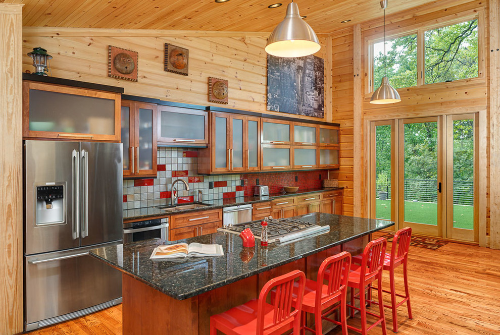 Photo of a mid-sized country galley kitchen in Charlotte with medium hardwood floors, an undermount sink, shaker cabinets, medium wood cabinets, red splashback, stainless steel appliances and with island.