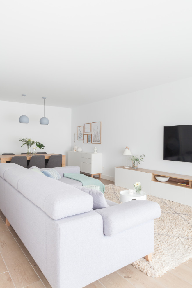 This is an example of a large scandinavian open concept living room in Madrid with white walls, ceramic floors, no fireplace, a wall-mounted tv and brown floor.
