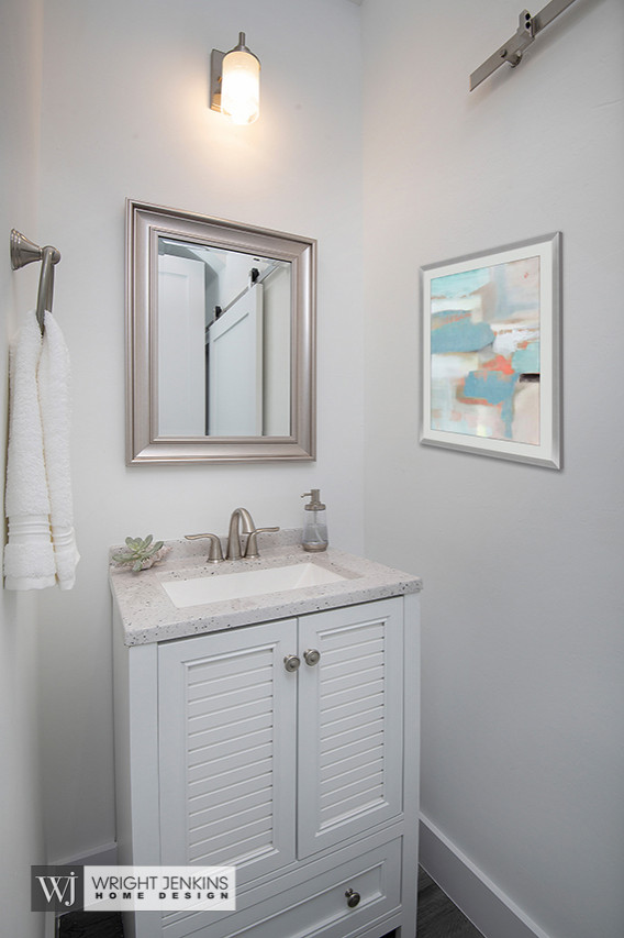 This is an example of a mid-sized beach style powder room in Other with flat-panel cabinets, white cabinets, a two-piece toilet, white walls, medium hardwood floors, an undermount sink, terrazzo benchtops, grey floor, white benchtops and a freestanding vanity.