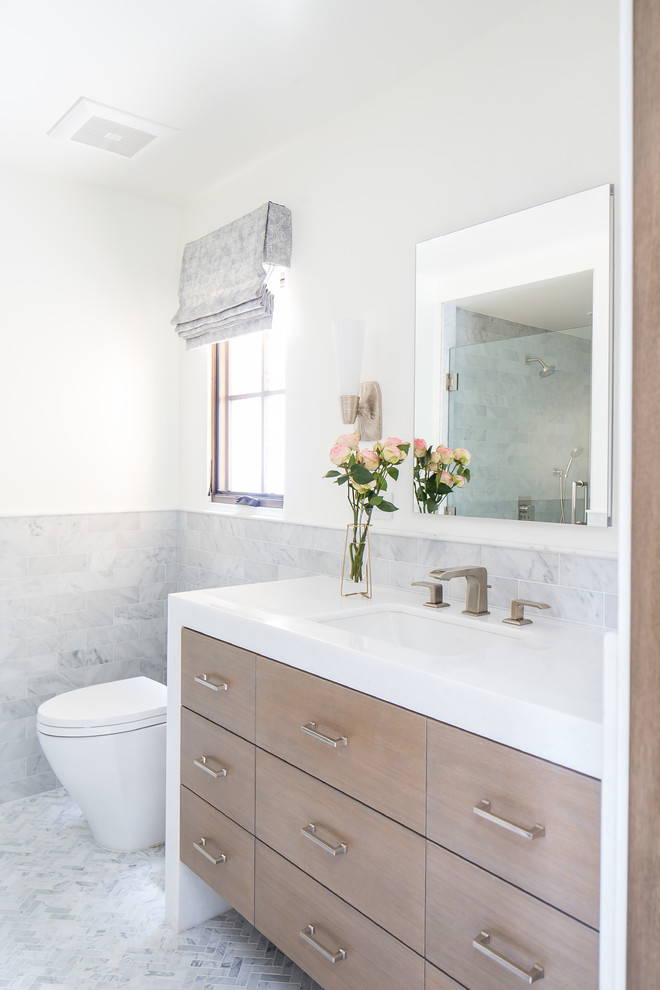 This is an example of a large mediterranean 3/4 bathroom in Orange County with flat-panel cabinets, medium wood cabinets, an alcove shower, gray tile, white walls, an undermount sink, grey floor, a hinged shower door and white benchtops.