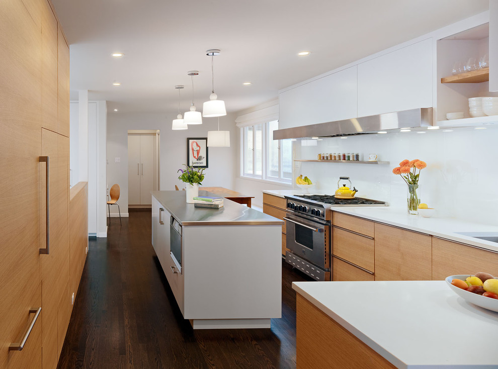 Contemporary eat-in kitchen in San Francisco with stainless steel appliances, flat-panel cabinets, light wood cabinets, white splashback, glass sheet splashback and stainless steel benchtops.