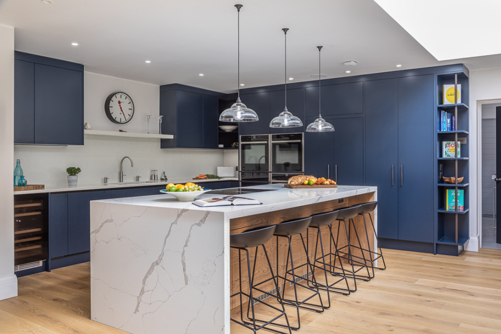 Inspiration for a contemporary kitchen remodel in Buckinghamshire with flat-panel cabinets, blue cabinets, an island and white countertops