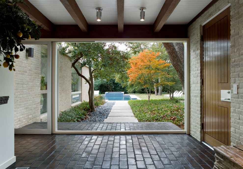 Photo of a mid-sized midcentury entryway in Dallas with white walls and brick floors.