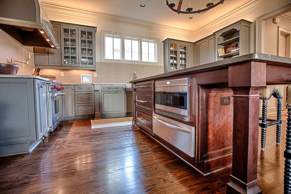 Open concept kitchen - large rustic u-shaped medium tone wood floor open concept kitchen idea in Birmingham with a farmhouse sink, flat-panel cabinets, gray cabinets, limestone countertops, beige backsplash, stone tile backsplash, stainless steel appliances and an island