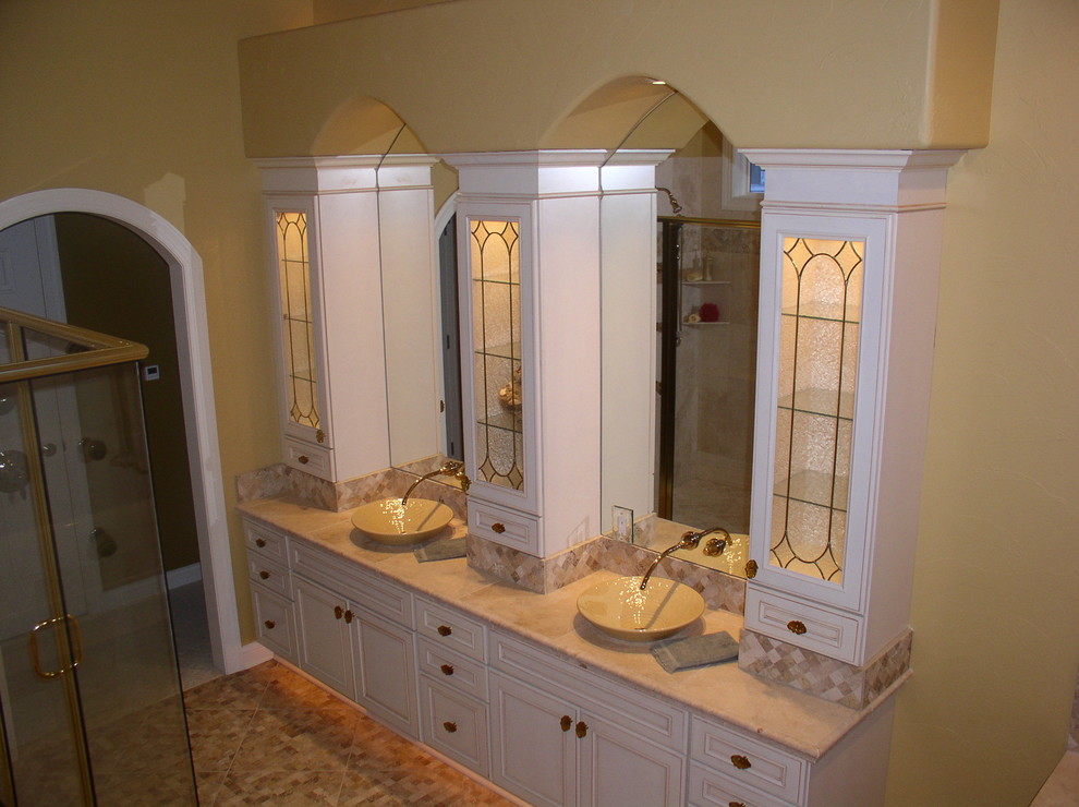 Photo of a mid-sized traditional bathroom in Milwaukee with a vessel sink, raised-panel cabinets, white cabinets, tile benchtops, a drop-in tub, an open shower, a one-piece toilet, beige tile, stone tile, yellow walls and travertine floors.