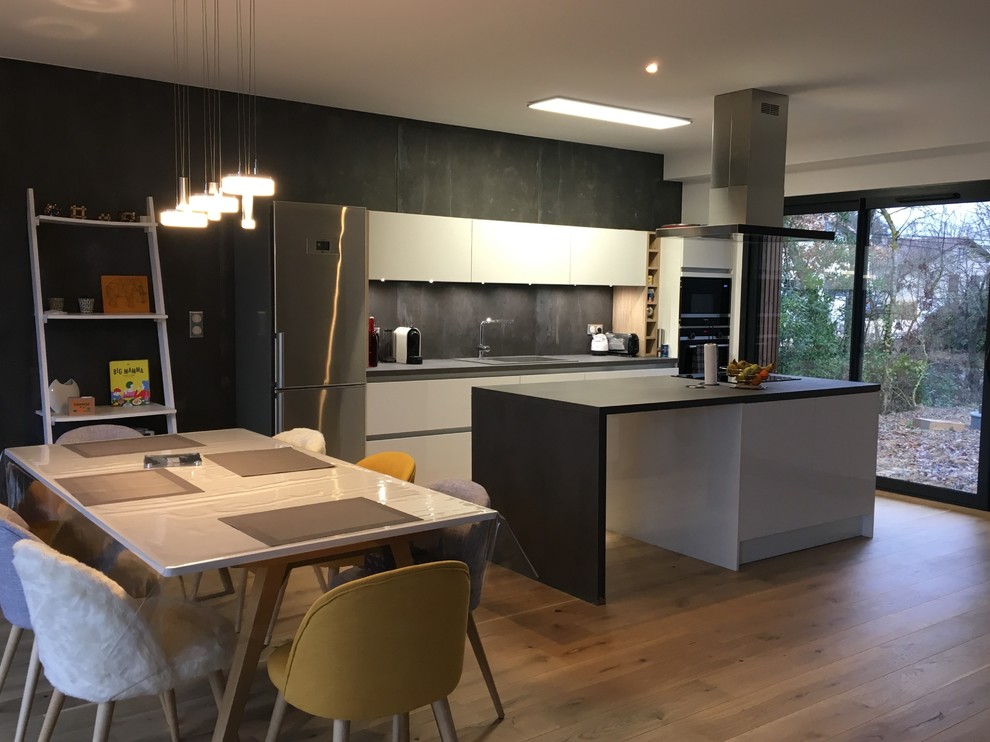 Design ideas for a mid-sized contemporary galley open plan kitchen in Toulouse with a single-bowl sink, laminate benchtops, panelled appliances, with island, grey benchtop, beaded inset cabinets, stainless steel cabinets, grey splashback, ceramic splashback, light hardwood floors and brown floor.