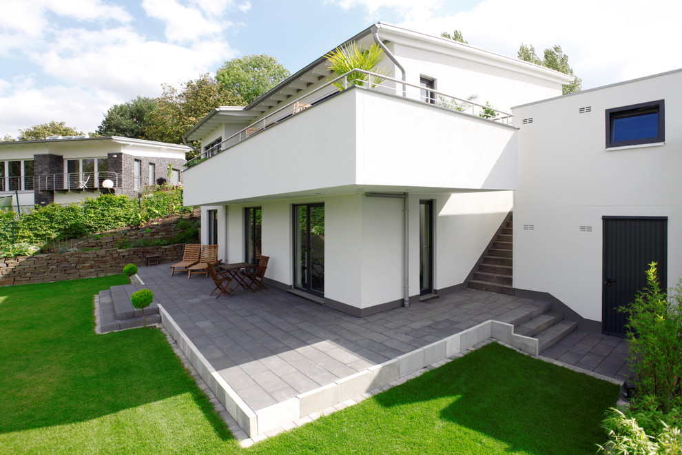 Design ideas for a large contemporary two-storey stucco white exterior in Dortmund with a shed roof.
