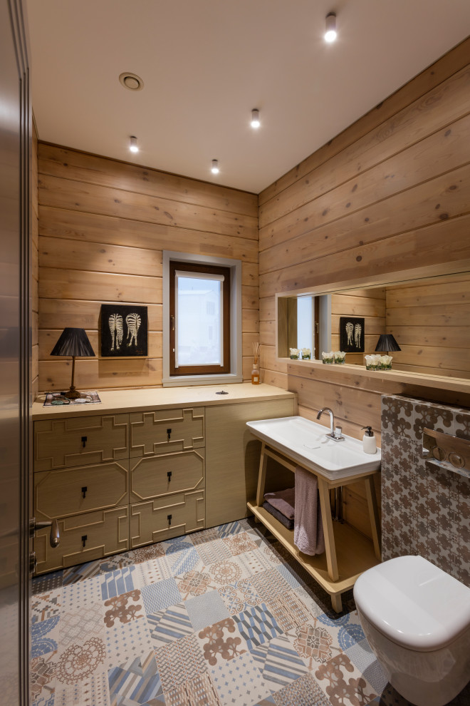 Идея дизайна: ванная комната в стиле рустика с инсталляцией, коричневыми стенами, консольной раковиной, разноцветным полом, тумбой под одну раковину, напольной тумбой и деревянными стенами