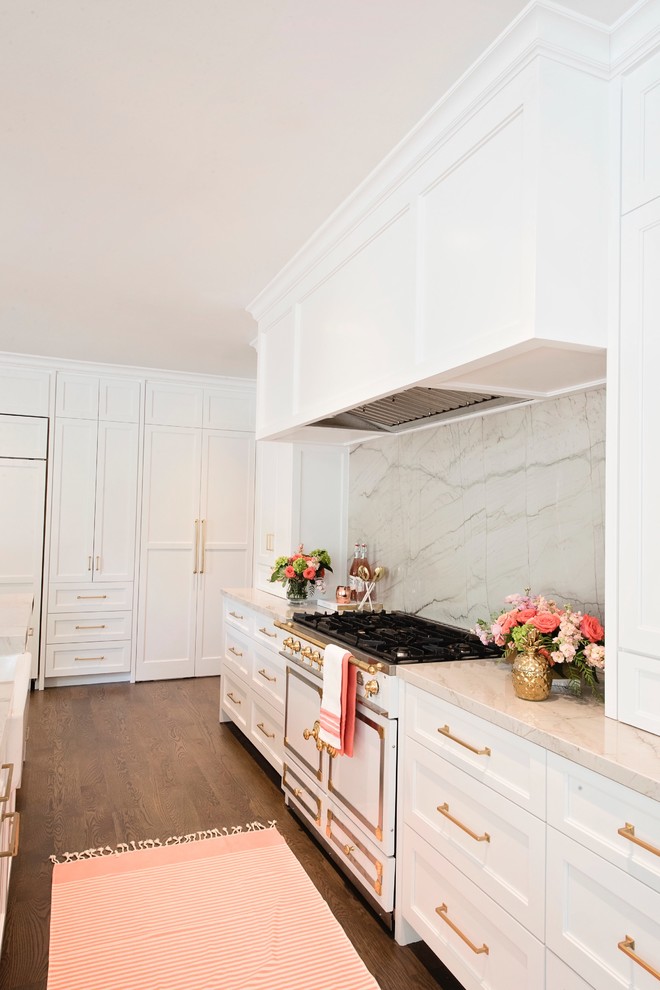 Large transitional l-shaped medium tone wood floor and brown floor open concept kitchen photo with a farmhouse sink, recessed-panel cabinets, white cabinets, quartzite countertops, white backsplash, stone slab backsplash, paneled appliances and an island