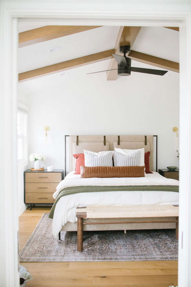 Ejemplo de dormitorio principal de estilo de casa de campo de tamaño medio con paredes blancas, suelo de madera clara, suelo marrón y todos los tratamientos de pared
