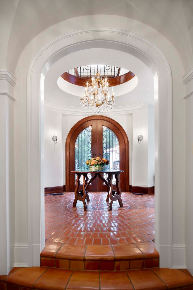 Inspiration for a mediterranean foyer in Chicago with white walls, terra-cotta floors, a double front door, a glass front door and red floor.