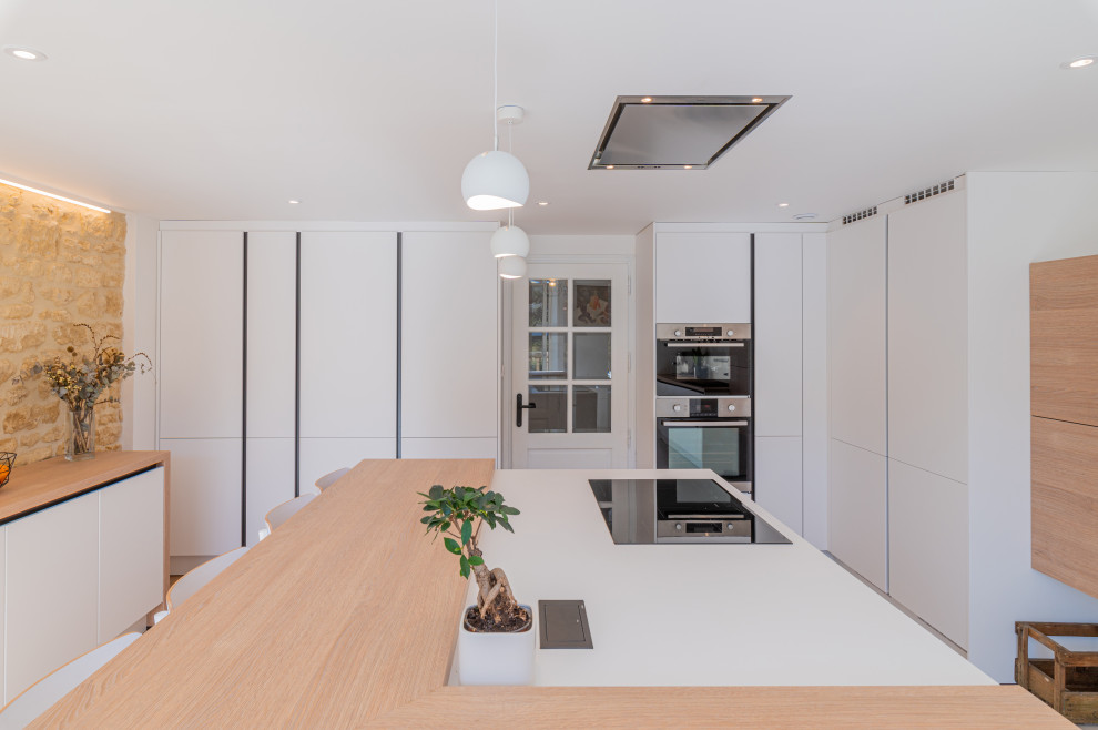 Medium sized contemporary l-shaped enclosed kitchen in Other with a single-bowl sink, beaded cabinets, white cabinets, wood worktops, white splashback, glass sheet splashback, stainless steel appliances and an island.