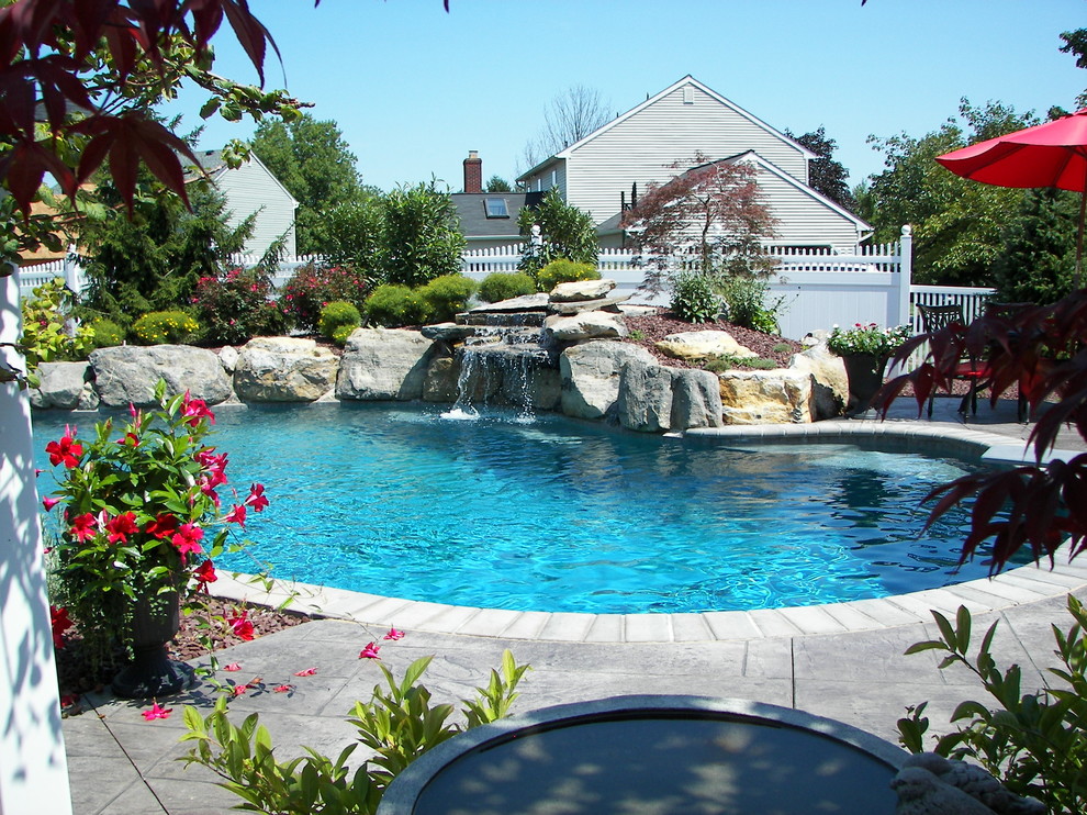 This is an example of a traditional backyard custom-shaped natural pool in Philadelphia with stamped concrete.