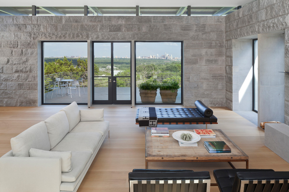 Large modern formal open concept living room in Austin with light hardwood floors, a freestanding tv and grey walls.