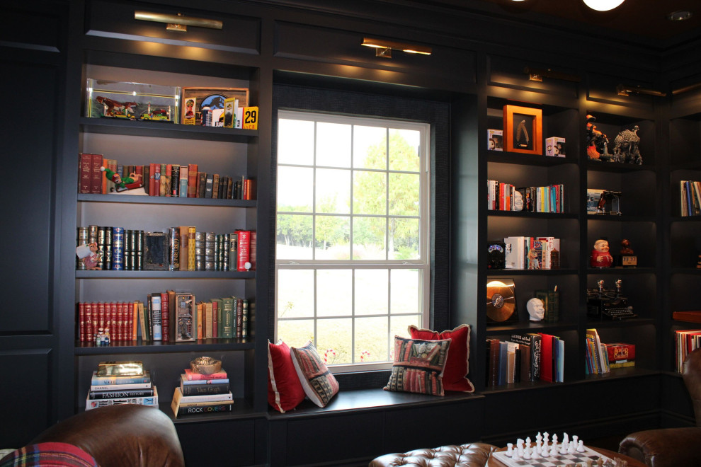Amerikansk inredning av ett mellanstort arbetsrum, med ett bibliotek, svarta väggar, mörkt trägolv, en bred öppen spis, en spiselkrans i gips, ett inbyggt skrivbord och brunt golv