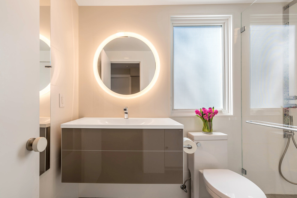 Inspiration for a small modern 3/4 bathroom in San Francisco with flat-panel cabinets, brown cabinets, an alcove shower, a one-piece toilet, multi-coloured tile, glass tile, white walls, porcelain floors, an integrated sink, glass benchtops, grey floor, a hinged shower door and white benchtops.