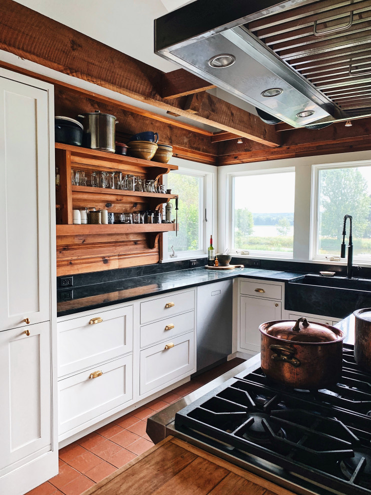 Inspiration for a mid-sized country l-shaped kitchen in New York with a farmhouse sink, beaded inset cabinets, white cabinets, soapstone benchtops, stainless steel appliances, ceramic floors, with island, red floor and black benchtop.