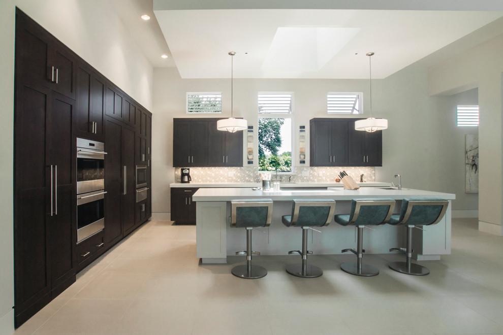 Kitchen pantry - large transitional l-shaped kitchen pantry idea in Miami with shaker cabinets, dark wood cabinets, quartz countertops, beige backsplash, paneled appliances and an island
