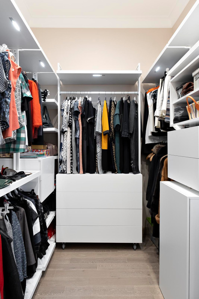 This is an example of a small contemporary women's walk-in wardrobe in Moscow with medium hardwood floors and beige floor.