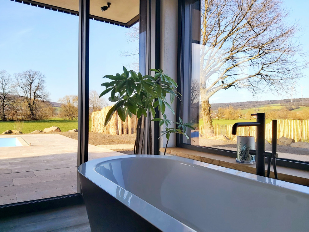 This is an example of an expansive contemporary bathroom in Frankfurt with a freestanding tub, a curbless shower, a two-piece toilet, an open shower and a single vanity.