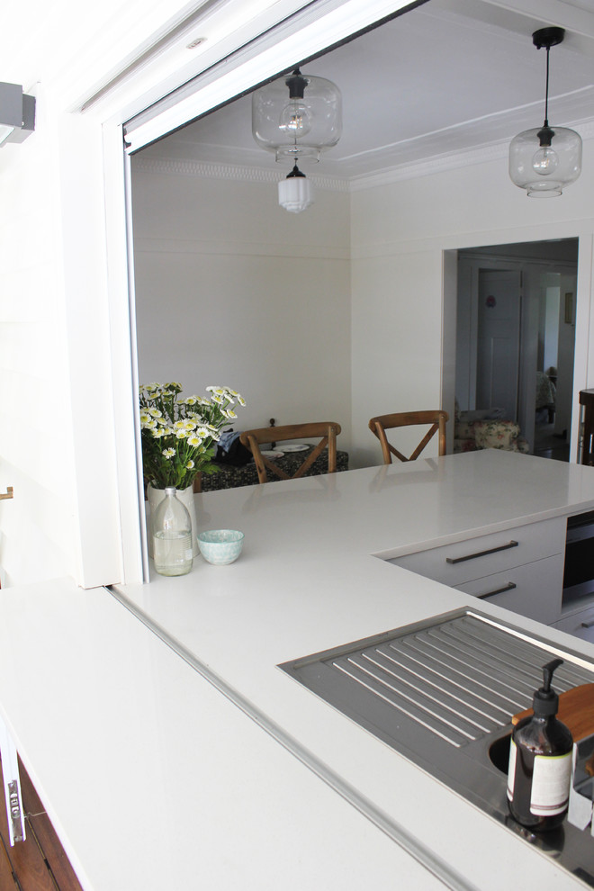 Contemporary kitchen in Brisbane with a drop-in sink, flat-panel cabinets, white cabinets, quartz benchtops, white splashback, subway tile splashback and stainless steel appliances.