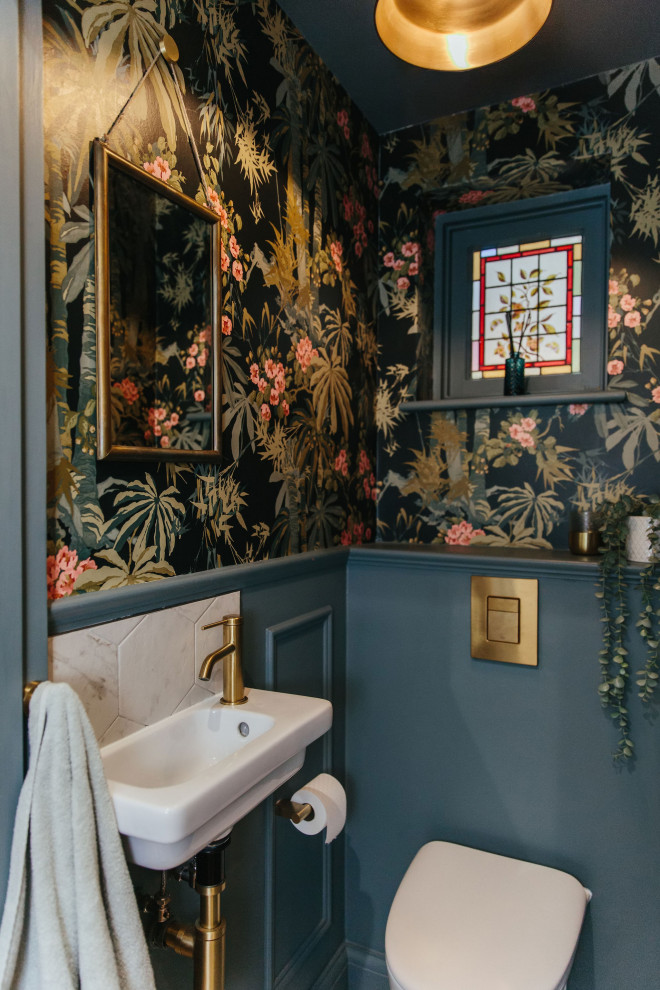 Eklektisk inredning av ett litet toalett, med en vägghängd toalettstol, blå väggar och ett väggmonterat handfat
