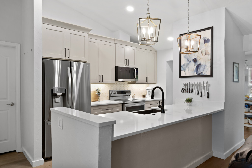 Small transitional galley eat-in kitchen in Orlando with a farmhouse sink, shaker cabinets, beige cabinets, quartz benchtops, beige splashback, marble splashback, stainless steel appliances, laminate floors, grey floor, white benchtop and vaulted.