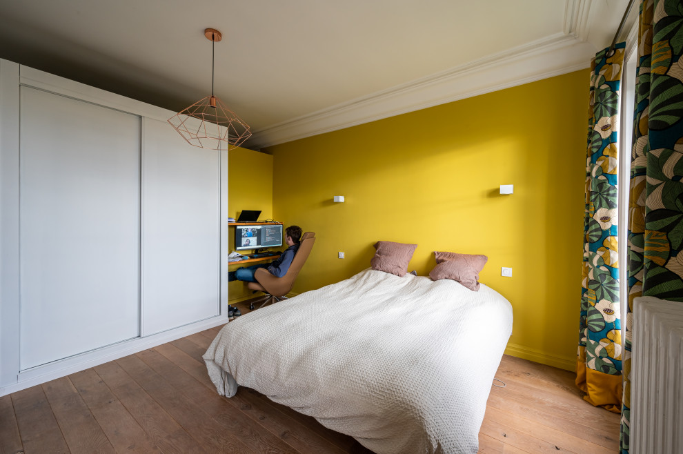 Ejemplo de dormitorio principal contemporáneo grande sin chimenea con paredes amarillas, suelo de madera clara y suelo marrón