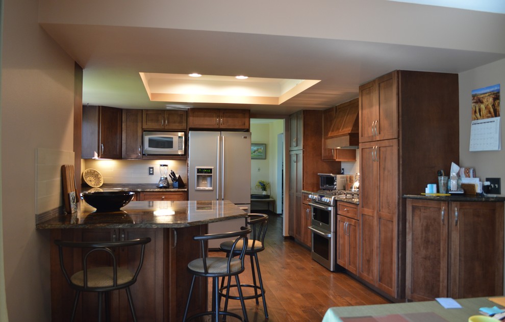 Design ideas for a mid-sized arts and crafts u-shaped separate kitchen in Denver with an undermount sink, recessed-panel cabinets, medium wood cabinets, granite benchtops, beige splashback, porcelain splashback, stainless steel appliances, medium hardwood floors and no island.