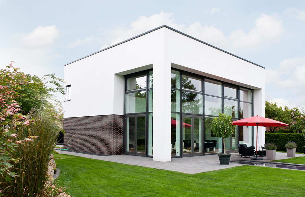 This is an example of a mid-sized modern two-storey brick white exterior in Bremen with a flat roof.