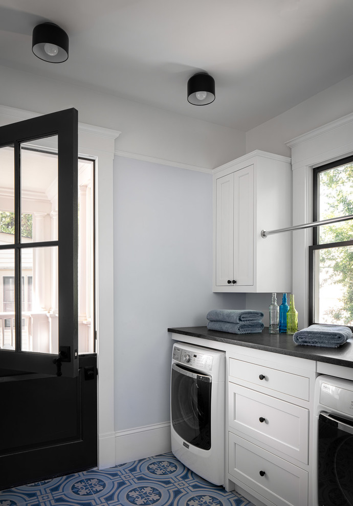 This is an example of a large transitional dedicated laundry room in Atlanta with shaker cabinets, white cabinets, quartz benchtops, blue walls, ceramic floors, a side-by-side washer and dryer, black benchtop and multi-coloured floor.