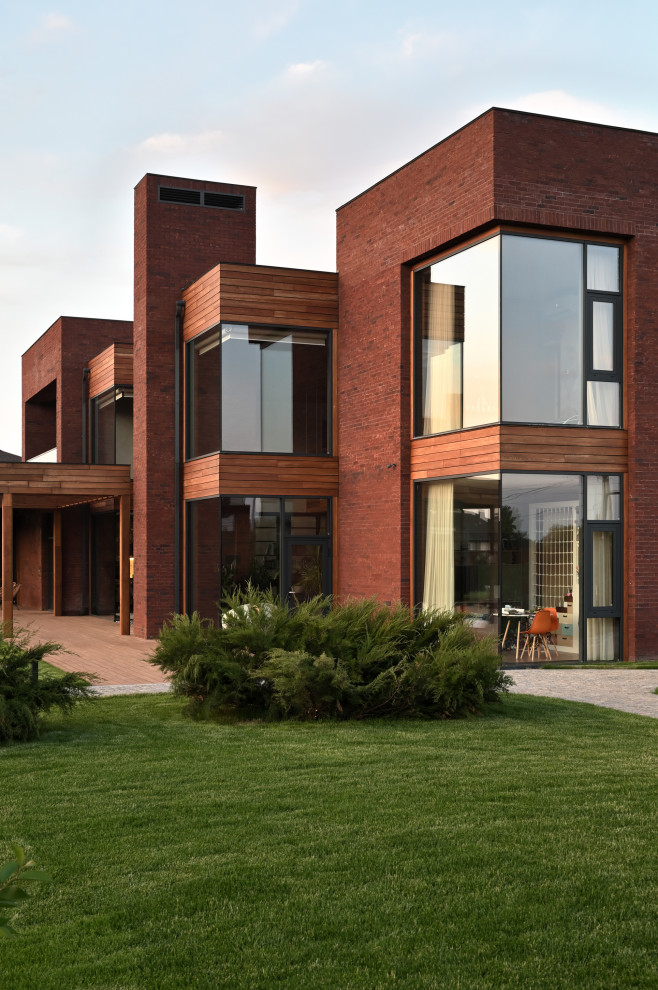 Inspiration pour une grande façade de maison marron design en brique à un étage avec un toit plat.