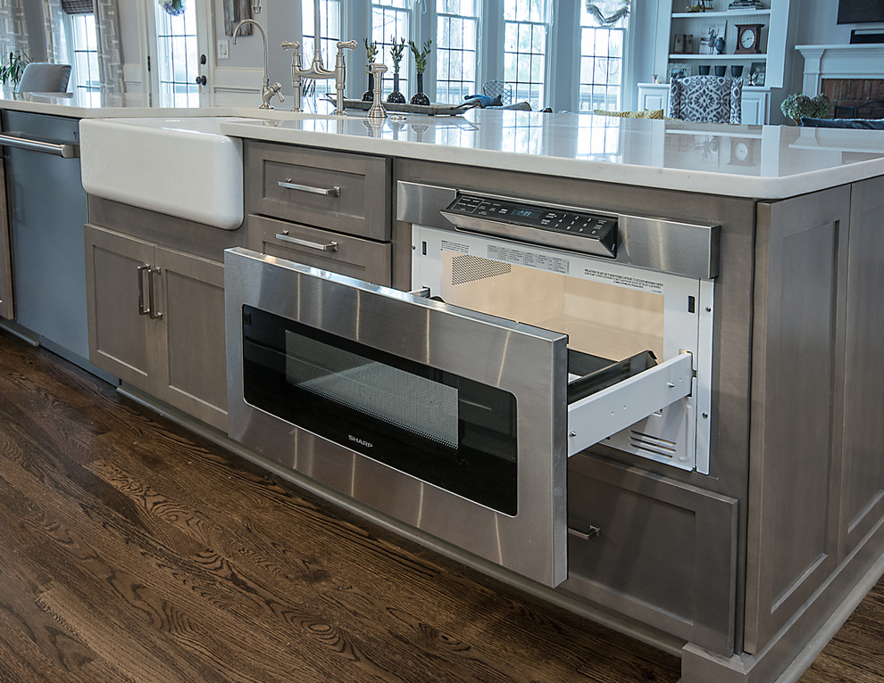 Inspiration for a large transitional l-shaped medium tone wood floor and brown floor open concept kitchen remodel in Atlanta with a farmhouse sink, shaker cabinets, white cabinets, quartzite countertops, white backsplash, subway tile backsplash, stainless steel appliances and an island