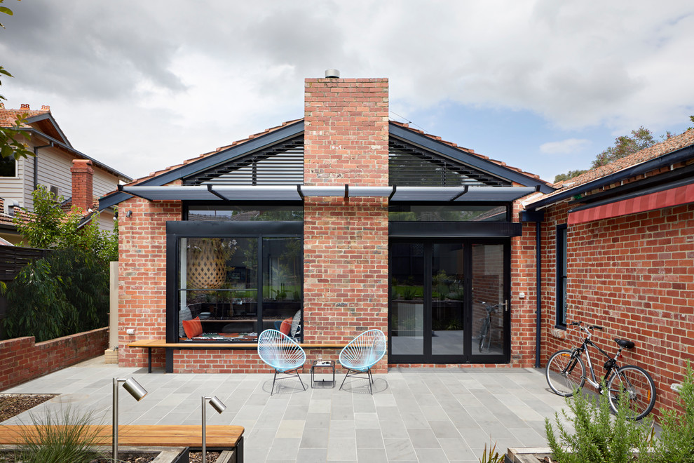 Photo of a transitional one-storey brick red house exterior in Melbourne with a gable roof and a tile roof.