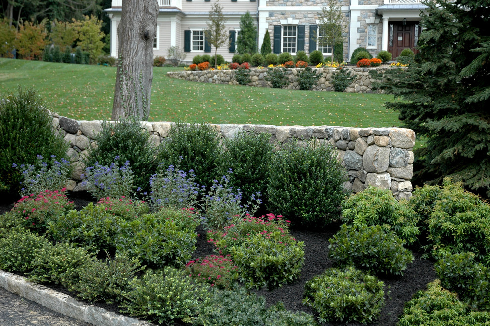 Mid-sized traditional front yard full sun formal garden in New York with a retaining wall and natural stone pavers.