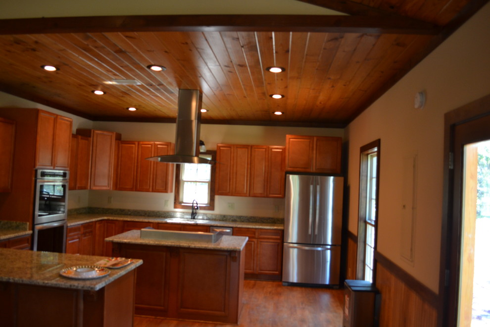 Inspiration for a mid-sized rustic u-shaped medium tone wood floor kitchen remodel in Atlanta with raised-panel cabinets, brown cabinets, granite countertops, stainless steel appliances and an island