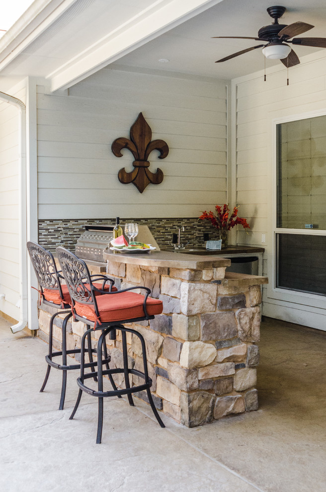 This is an example of a traditional backyard patio in Dallas with an outdoor kitchen, concrete slab and a roof extension.