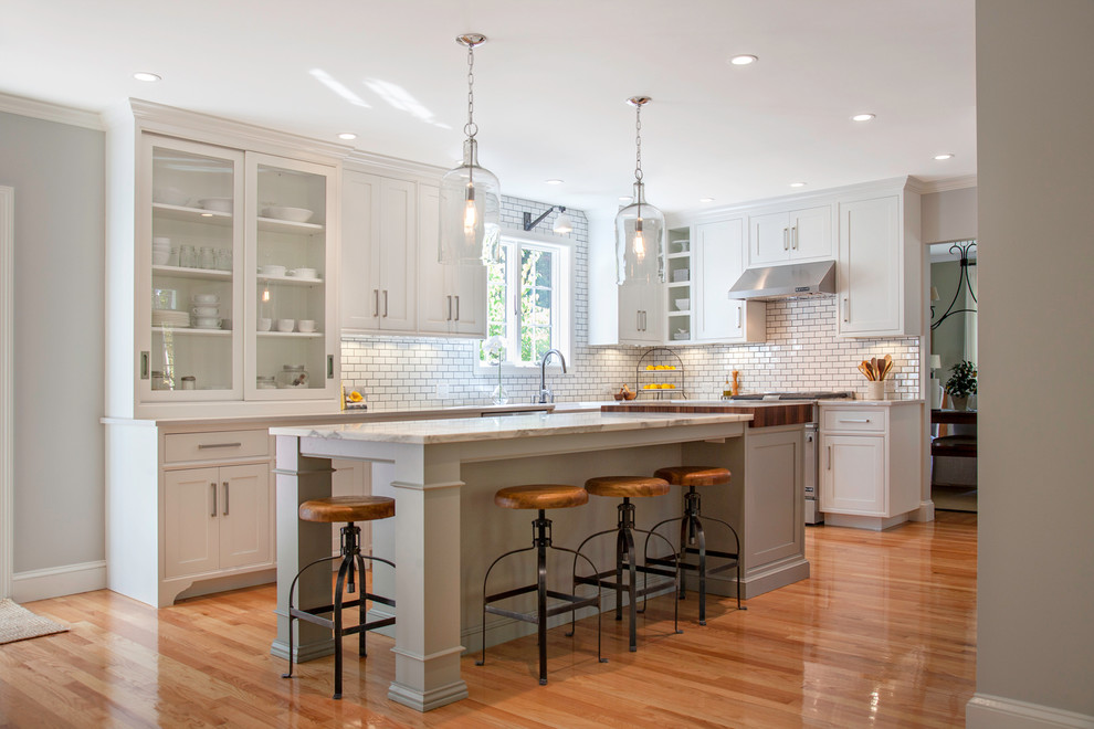 This is an example of a country kitchen in Boston with white cabinets, white splashback, subway tile splashback and stainless steel appliances.
