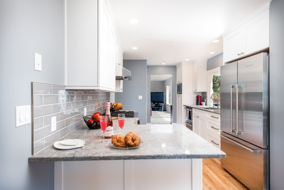 Design ideas for a small galley eat-in kitchen in Seattle with an undermount sink, shaker cabinets, white cabinets, quartz benchtops, grey splashback, porcelain splashback, coloured appliances, medium hardwood floors, a peninsula, blue floor and grey benchtop.