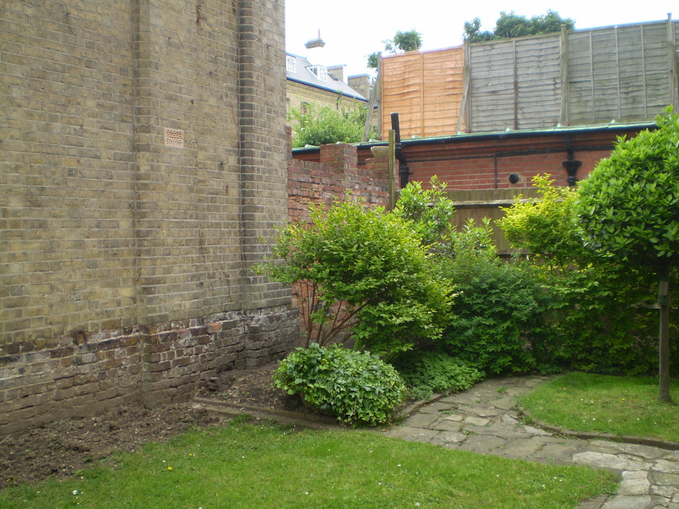 Photo of a mid-sized traditional courtyard full sun formal garden for summer in Sussex with a container garden and brick pavers.