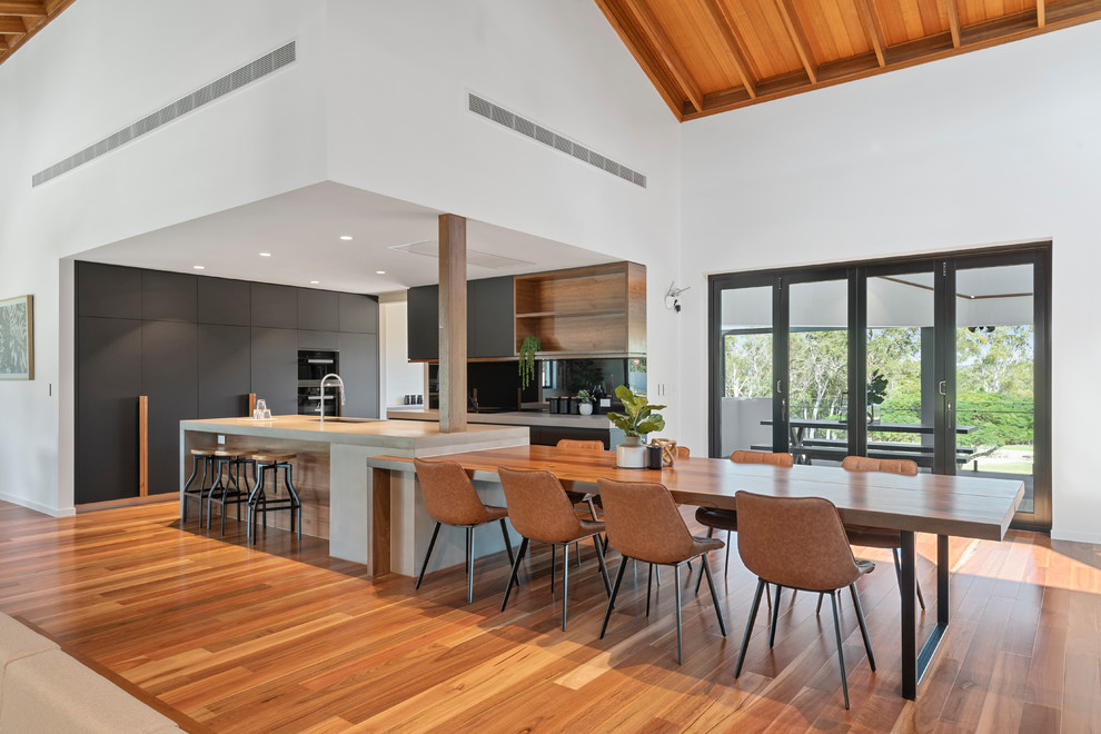 This is an example of a large scandinavian galley eat-in kitchen in Brisbane with mirror splashback, medium hardwood floors, with island and grey benchtop.